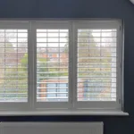 white full height shutters in a room with blue walls